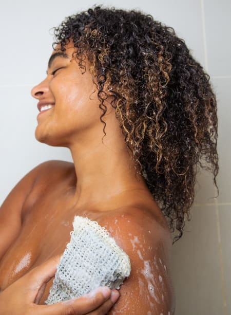 Young woman using the sisal bag as exfoliator in body with Detox, clarifying and exfoliating bar